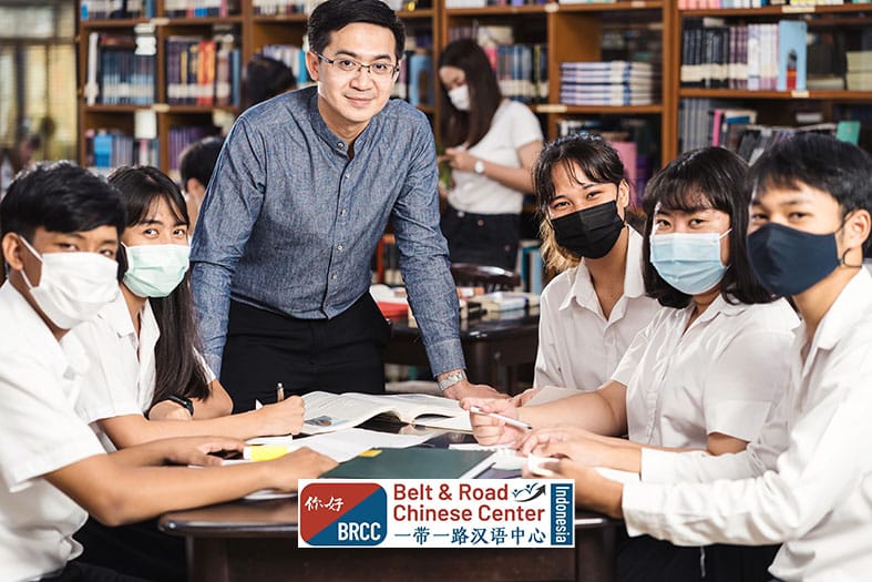 Dosen Asia berdiri di depan kelompok mahasiswa yang duduk di perpustakaan kelas universitas Tiongkok