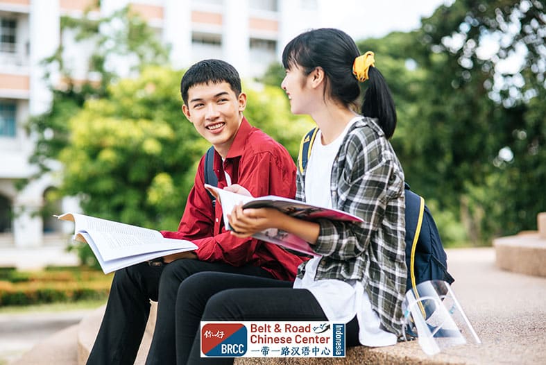 Mahasiswa laki-laki dan perempuan duduk membaca buku di tangga kampus universitas Tiongkok suasana akademik