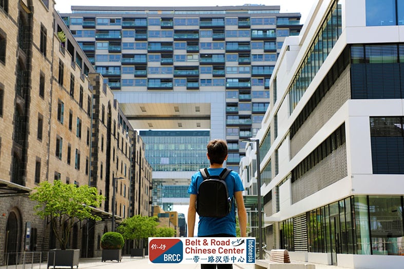 Mahasiswa baru tiba di kampus Tiongkok dengan ransel melihat gedung universitas modern